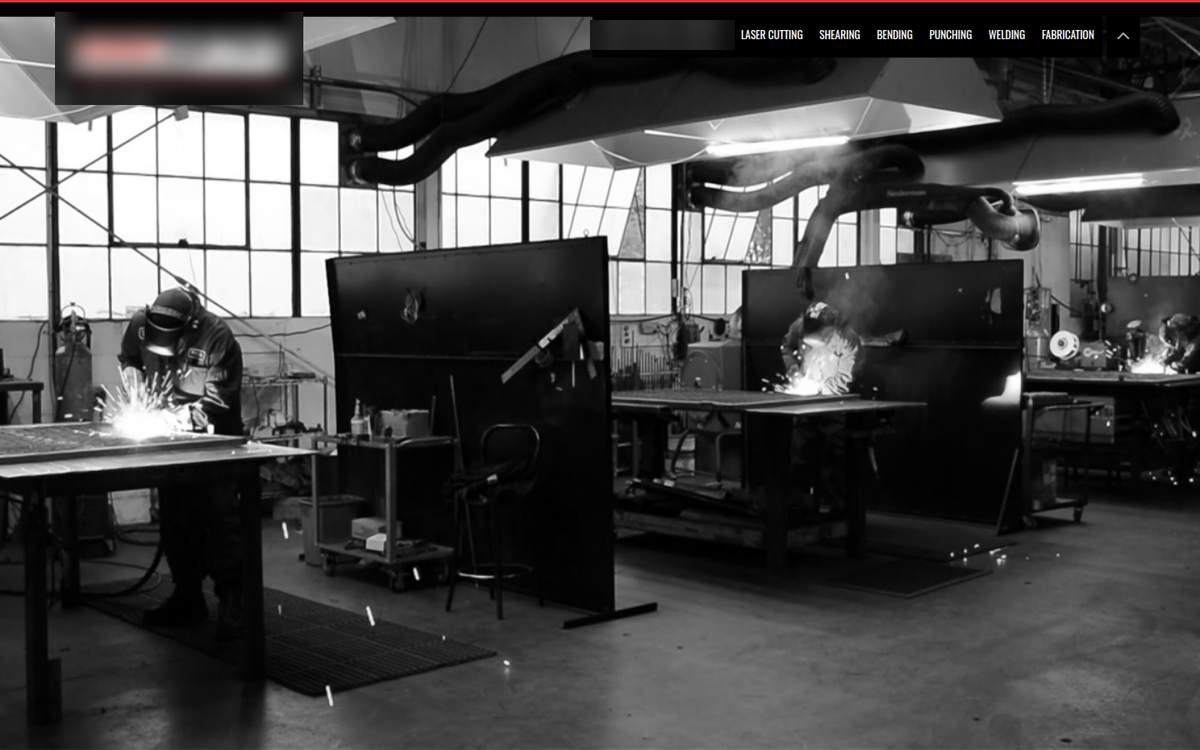 The old home page: a black and white workshop photo with a small menu and no headline or call to action. Company name hidden.